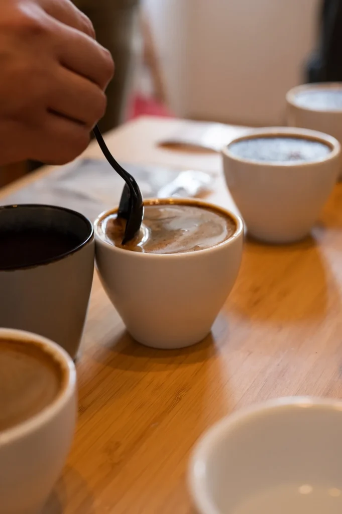 Kanállal törik meg a kávé kérgét egy cupping csészében